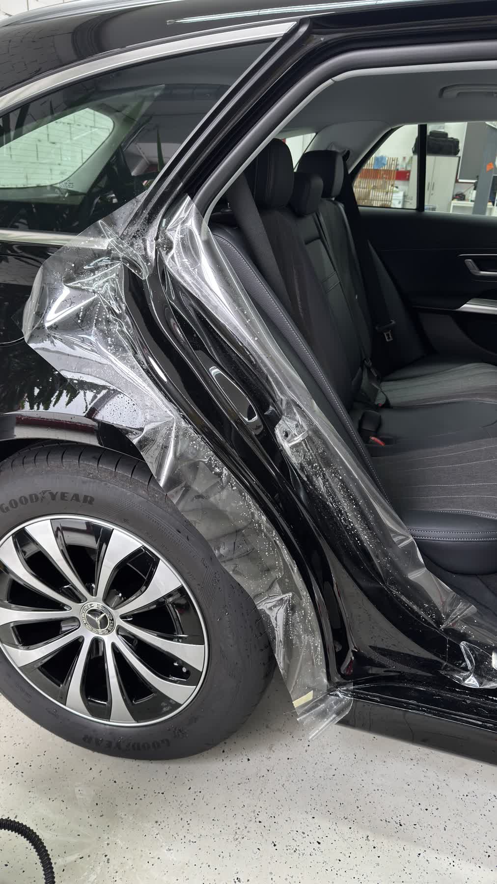 Lackschutzfolie wird am Einstieg eines schwarzen Mercedes verklebt